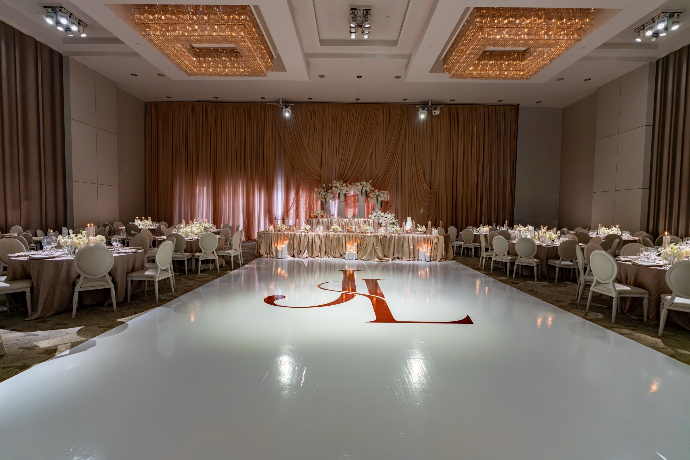 The Château Le Parc ballroom with taupe draping and the couple’s monogram on a white dance floor