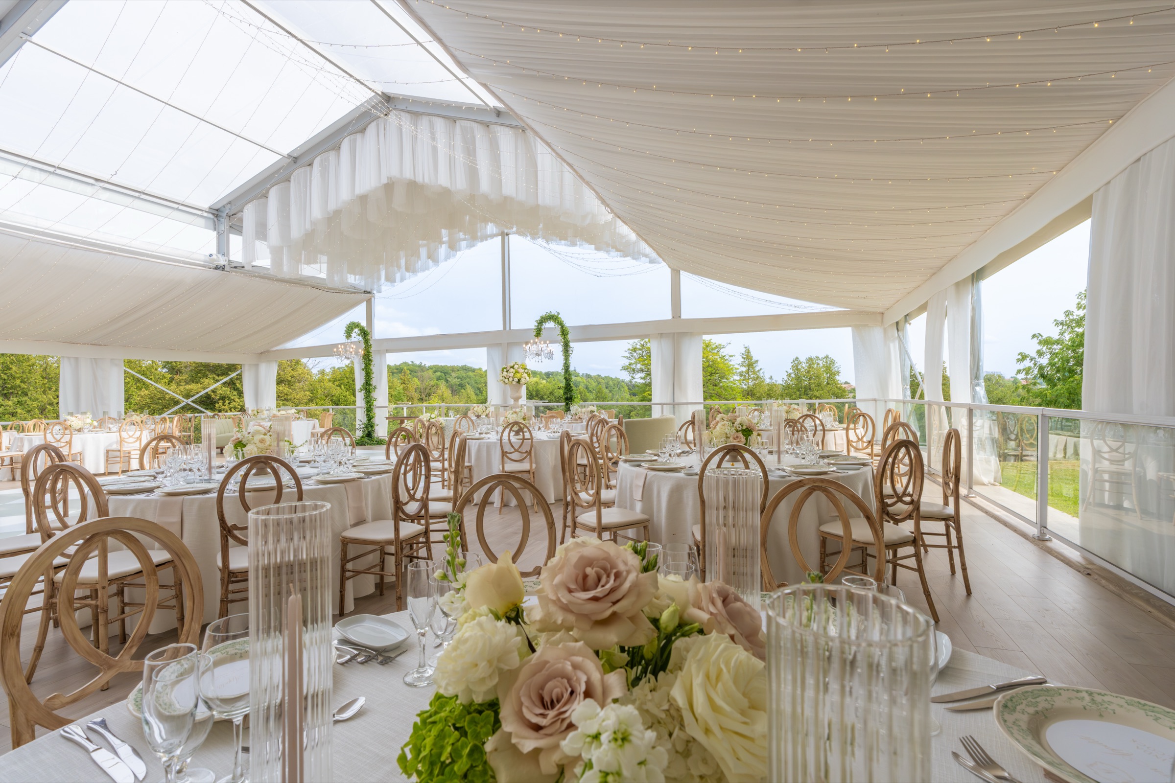 The tent set for dinner, seen past a centrepiece of white and blush roses